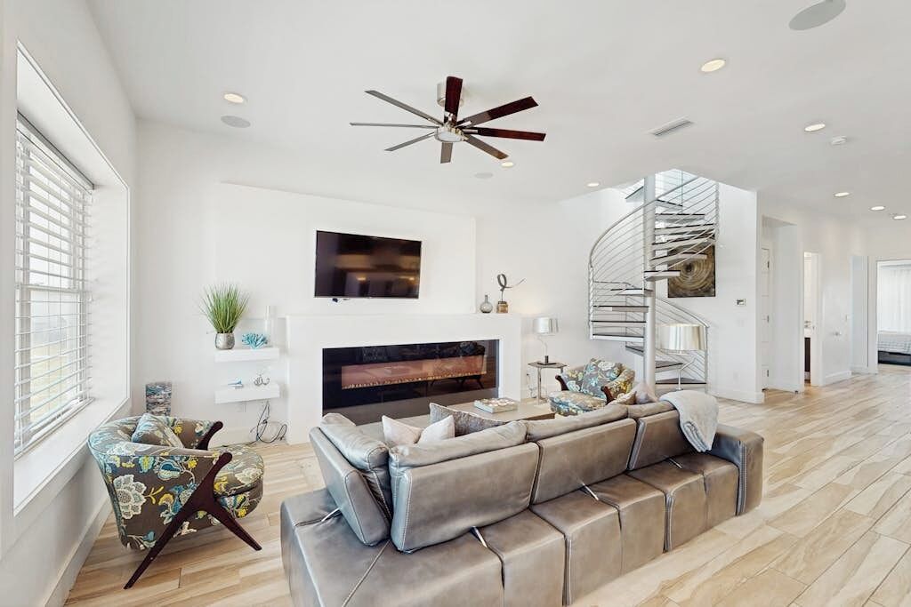 A modern living room with a fireplace, a sofa, a TV, and a spiral staircase.