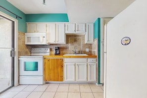 A compact kitchen with white cabinets, a wooden countertop, a stove, and a refrigerator. - Sand Dollar #5 - Canal-Front, Pool & Pier (Corpus Christi)