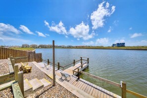 A wooden dock extending into a calm body of water, with a clear sky above. - Sand Dollar #5 - Canal-Front, Pool & Pier (Corpus Christi)