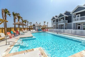 Ein Schwimmbad mit Liegestühlen und ein Gebäude mit Balkonen.