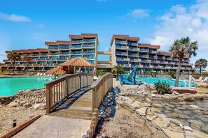 Un resort con edificios de varios pisos, una piscina y un puente de madera.