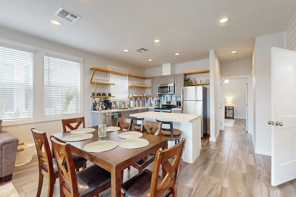 A modern kitchen with a central island, wooden dining table, and chairs.