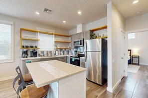 A modern kitchen with a central island, stainless steel appliances, and a breakfast bar. - Beach Bummz Bungalow (Port Aransas)