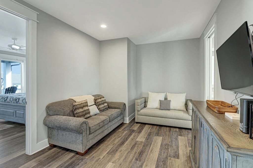 A living room with two sofas, a television, and a wooden cabinet.