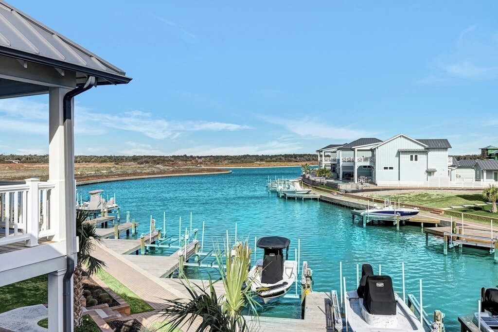 A marina with boats docked, a pool, and a white building with a porch.