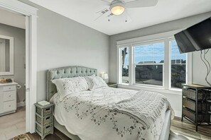 A bedroom with a bed, a ceiling fan, a window, and a television. - Reserve at St Charles Bay Reserve Lane Townhome 202 (Rockport)