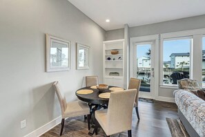 A dining area with a round table, chairs, and a view of the outside. - Reserve at St Charles Bay Reserve Lane Townhome 202 (Rockport)
