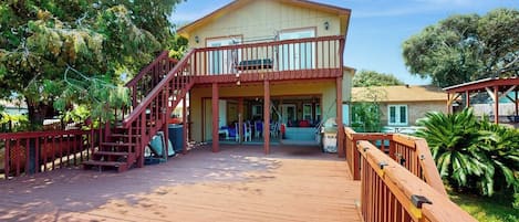 A two-story house with a wooden deck, a staircase, and a covered porch area.