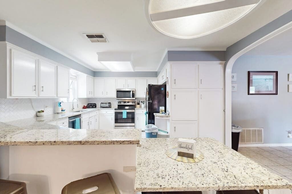 A modern kitchen with white cabinetry, granite countertops, and stainless steel appliances.