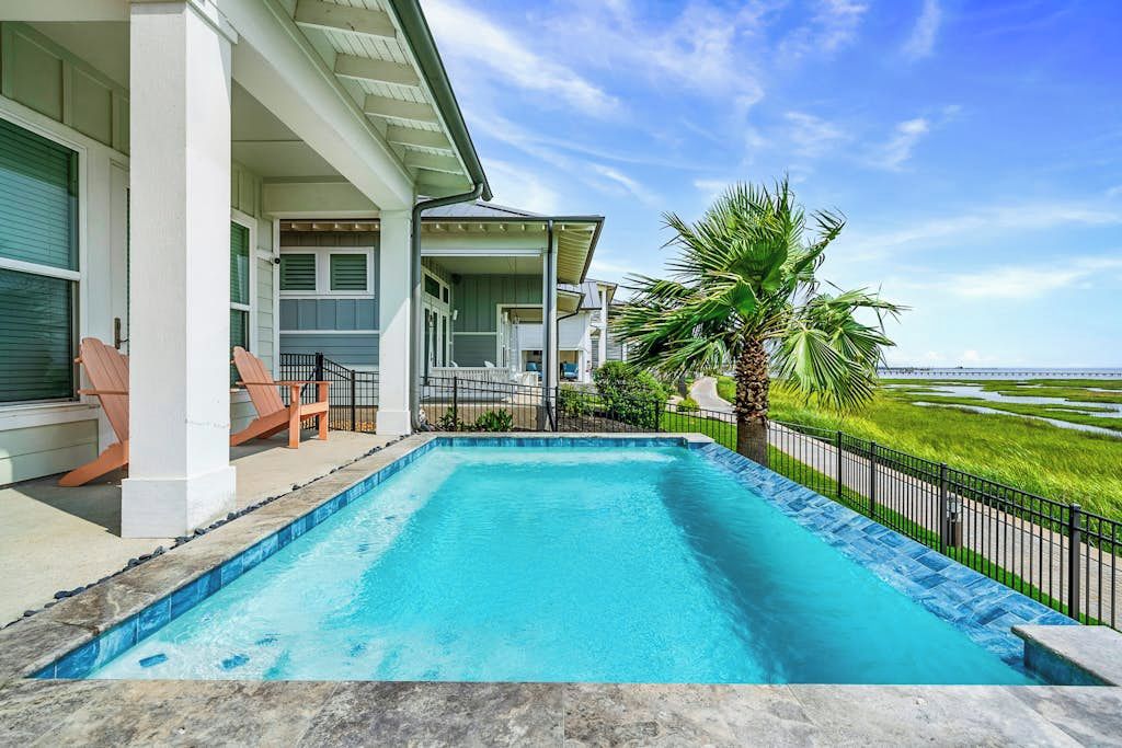 A swimming pool with a view of a green landscape and a building with a covered porch.