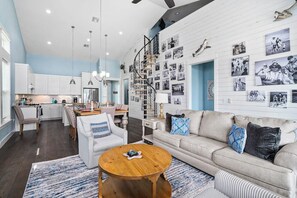 A modern living room with a sofa, coffee table, and a dining area with chairs and a table. - Bay Reserve - Bayfront, Private Heated Pool (Rockport)