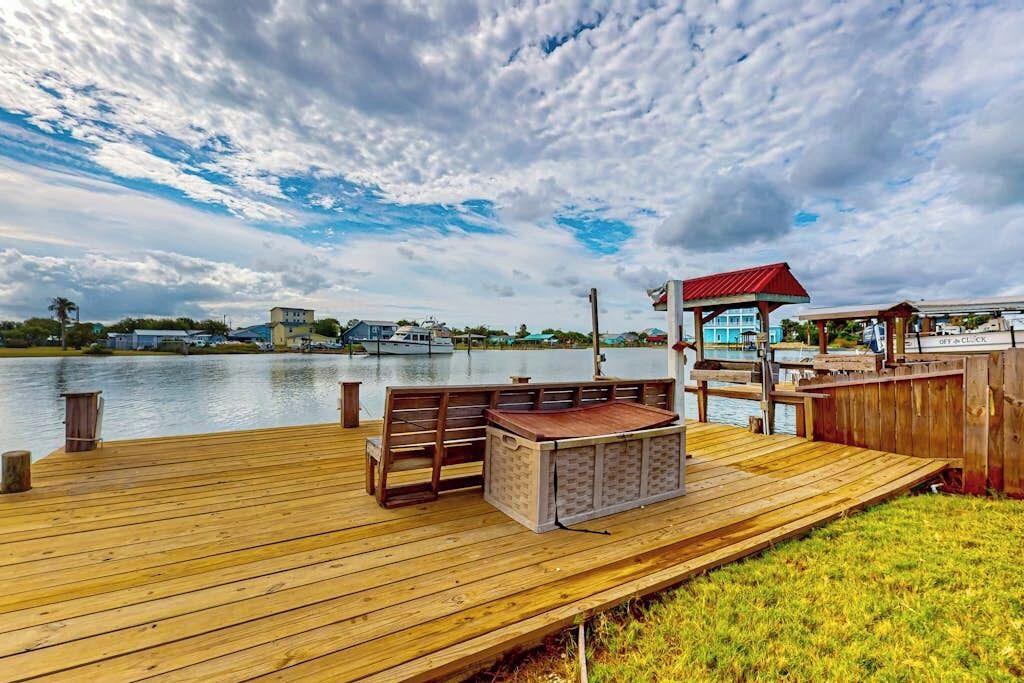 A wooden deck with a bench and a covered seating area overlooking a body of water.