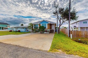 A residential area with a house featuring a front yard, a driveway, and a wooden fence. - Copano Bayfront Haven (Rockport)