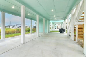 A covered outdoor corridor with white pillars, a concrete floor, and a view of houses in the distance. - Rockport Relaxation - Shared Pool, Golf Nearby (Rockport)