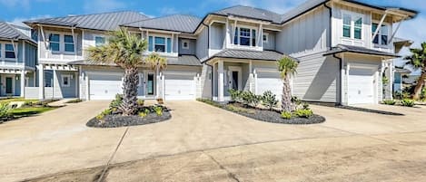 A residential building with a driveway, multiple garages, and landscaped areas with palm trees.