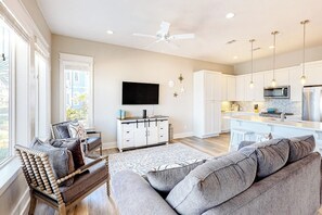 A modern living room with a sofa, a wooden chair, and a flat-screen TV.