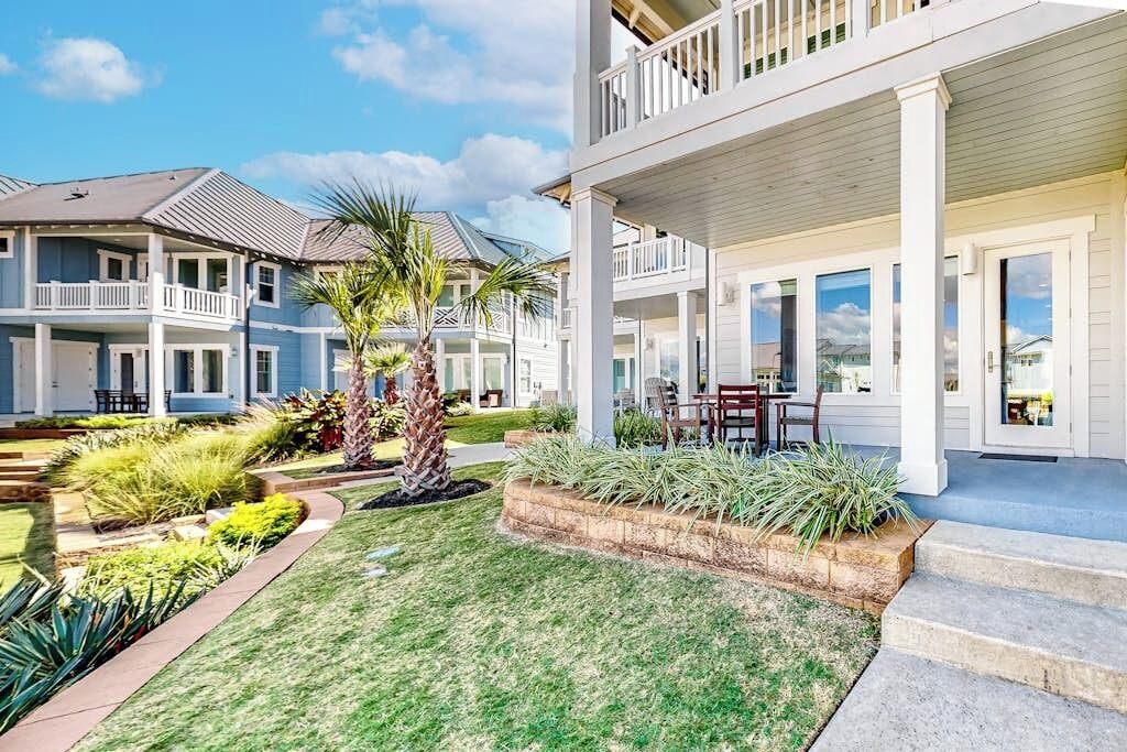 A residential property with a two-story house, a covered porch, and a well-maintained lawn.