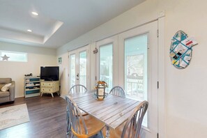 A dining area with a wooden table and chairs, a television, and a decorative lantern. - South Pearl Sailfish (Rockport)