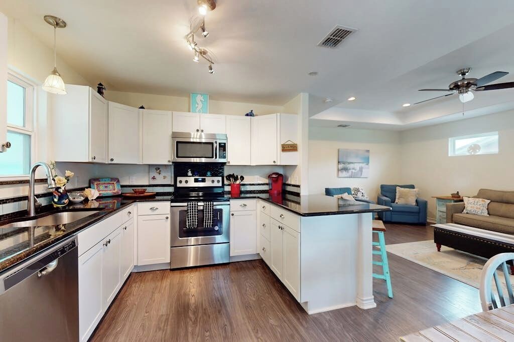 Een moderne keuken met witte kasten, roestvrijstalen apparatuur en een centraal eiland.