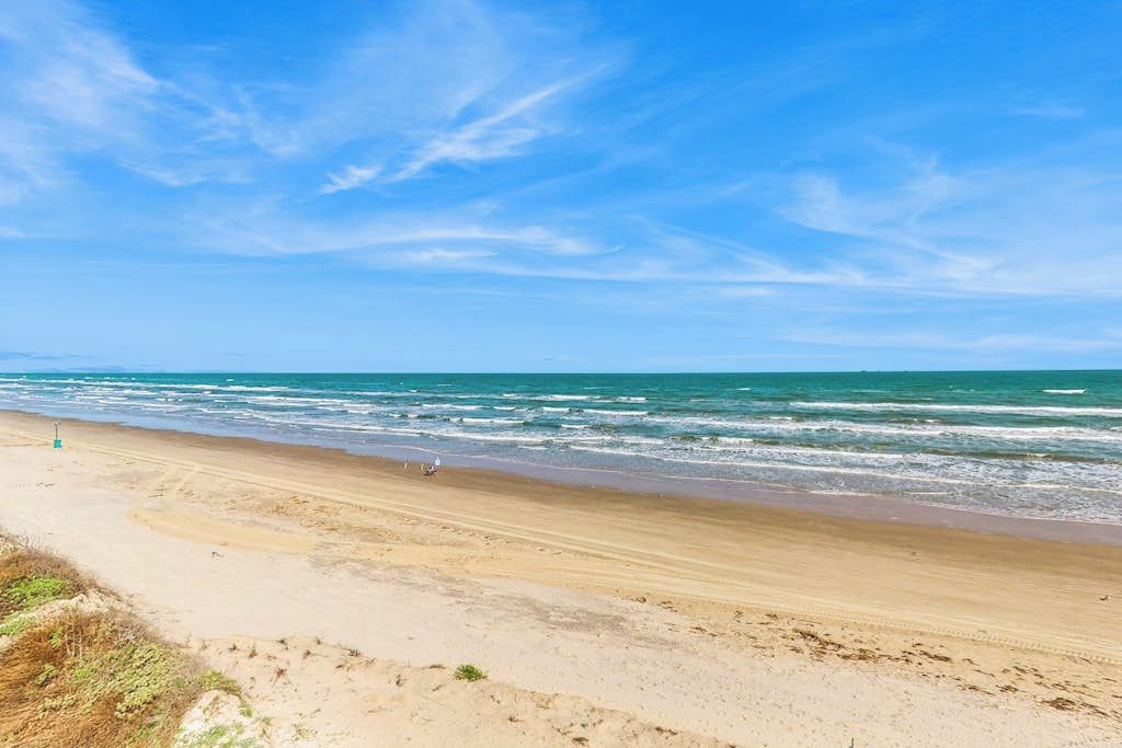 Une plage avec un ciel dégagé et une mer calme.