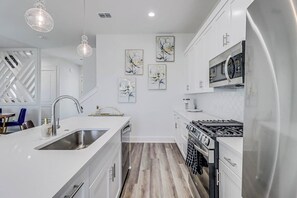 A modern kitchen with white cabinetry, a stainless steel sink, and a gas stove.