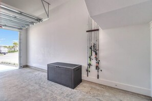 A garage with a concrete floor, a large gray storage unit, and fishing rods mounted on the wall.