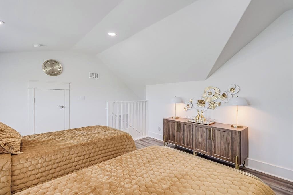 Une chambre avec deux lits, une armoire en bois, une horloge murale et un radiateur.