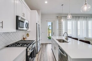 A modern kitchen with white cabinetry, stainless steel appliances, and a central island with a sink.