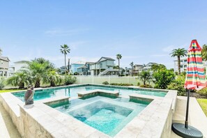 Ein Swimmingpool mit Steinrand, umgeben von Palmen und Häusern.
