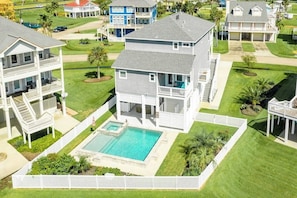 Ein zweistöckiges Haus mit Swimmingpool, umgeben von einem weißen Zaun und gepflegten Rasenflächen.