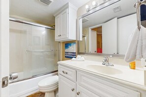 A bathroom with a shower, toilet, and vanity with a mirror and sink. - Seascape Gem - Ocean-View Balcony, Pool & Hot Tub (Galveston)