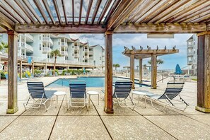 A poolside area with lounge chairs and a wooden pergola. - Seascape Condos #1222 (Galveston)