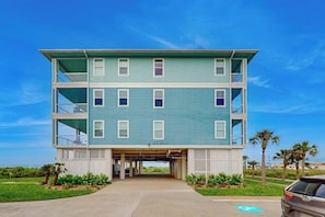 A multi-story building with a covered entrance and a parking area. - Pointe West Retreat Unit 302 (Galveston)