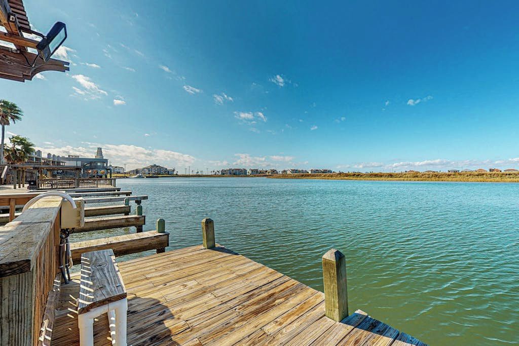 A wooden pier extending into calm water with a clear sky above.
