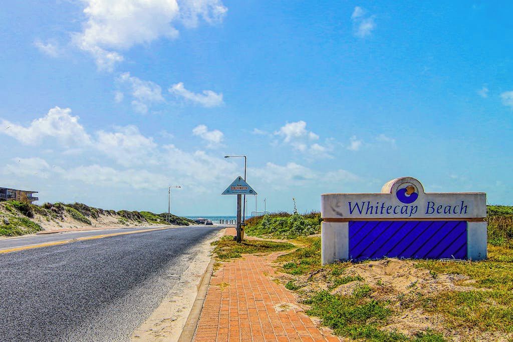 Een weg die naar een strand leidt, met een bord waarop 'Whitecap Beach' staat.