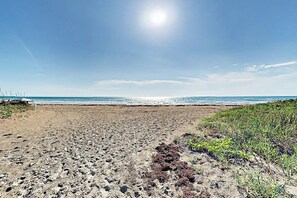 A sandy beach with footprints leading to the water, a clear sky, and a distant horizon. - Suntide II Condominiums #508 (South Padre Island)