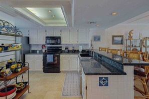 A kitchen with white cabinets, a black refrigerator, and a microwave. - Suntide II Condominiums #508 (South Padre Island)