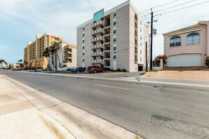 Un immeuble à plusieurs étages, doté d’une façade plate, de plusieurs balcons et d’un espace de stationnement à l’avant.