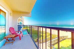 A balcony with a view of the ocean, two red chairs, and a small table. - Florence Condominiums #303 (South Padre Island)