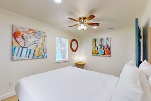 A bedroom with a bed, ceiling fan, and wall art. - Amberjack Oasis - Private Pool, Steps to Beach (South Padre Island)