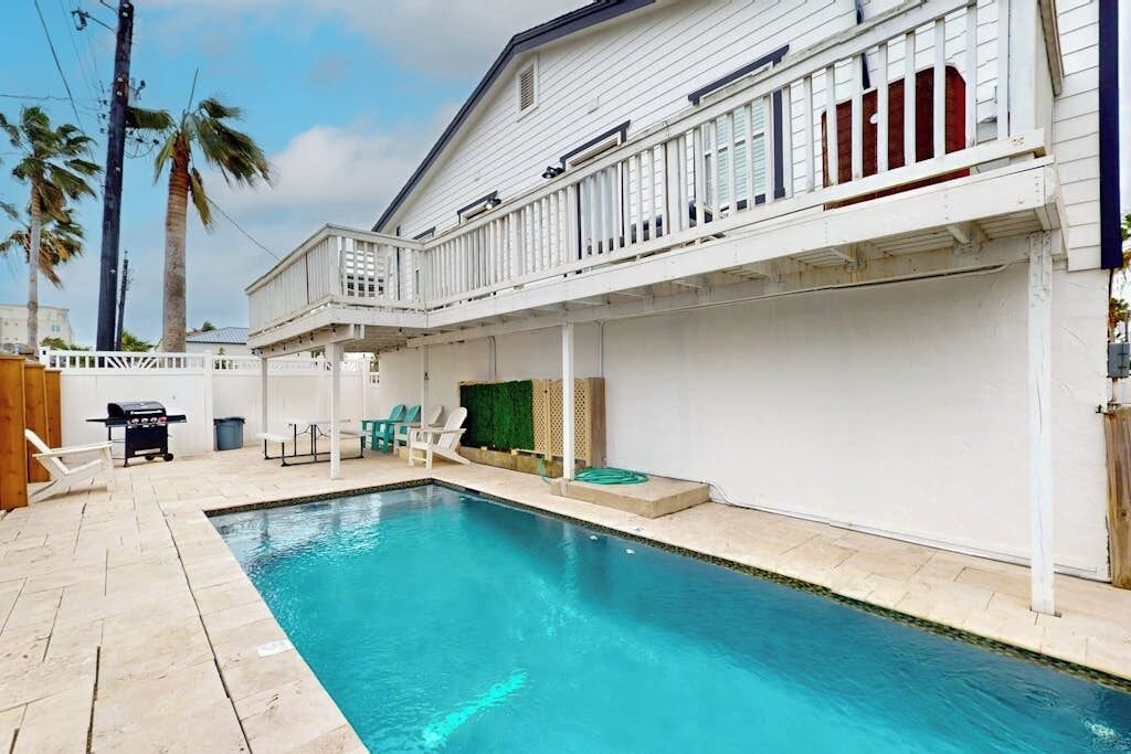 Propiedad residencial con piscina, mobiliario exterior y zona de patio cubierta.