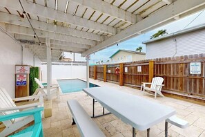 An outdoor pool area with a covered patio, a lifeguard stand, and a wooden fence. - Amberjack Oasis - Private Pool, Steps to Beach (South Padre Island)