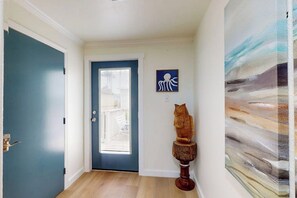 A hallway with a blue door, a wooden sculpture, and a painting. - Amberjack Oasis - Private Pool, Steps to Beach (South Padre Island)