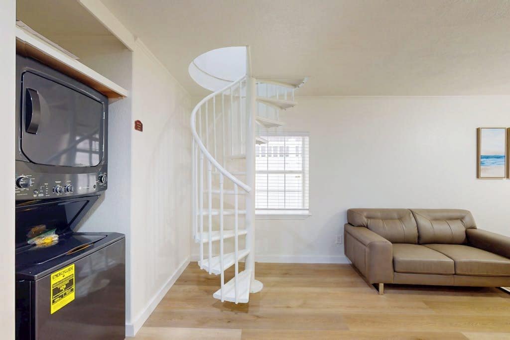 A living room with a spiral staircase, a sofa, and a television.