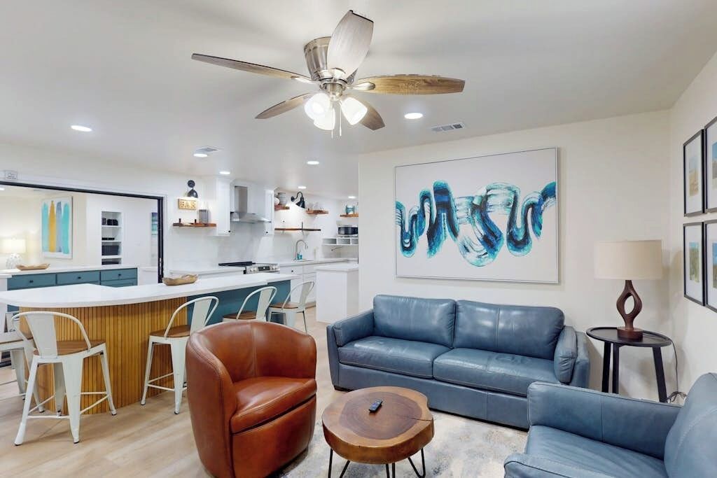 A modern living room with a blue sofa, a brown leather chair, and a wooden coffee table.