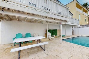 A poolside area with a picnic table and chairs, a covered seating area, and a pool. - Amberjack Oasis - Private Pool, Steps to Beach (South Padre Island)