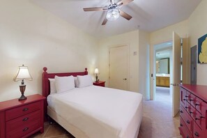 A bedroom with a bed, two bedside tables with lamps, a ceiling fan, and a wardrobe. - Sapphire Condominiums #303 (South Padre Island)