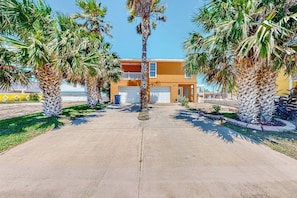 A residential property with a two-story building, a driveway, and palm trees. - Cora Lee - Private Pool & Putting Green (South Padre Island)
