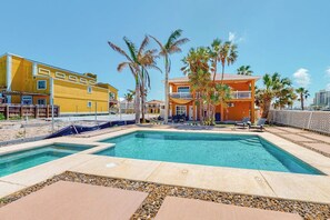 Área de piscina com céu claro, palmeiras e edifícios ao fundo.