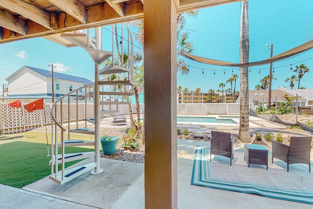 A covered outdoor area with a spiral staircase, outdoor seating, and a pool.